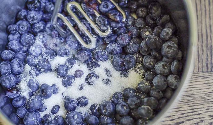 mashing blueberries and sugar in a saucepan
