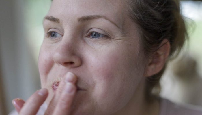 woman applying a lip scrub to her lips