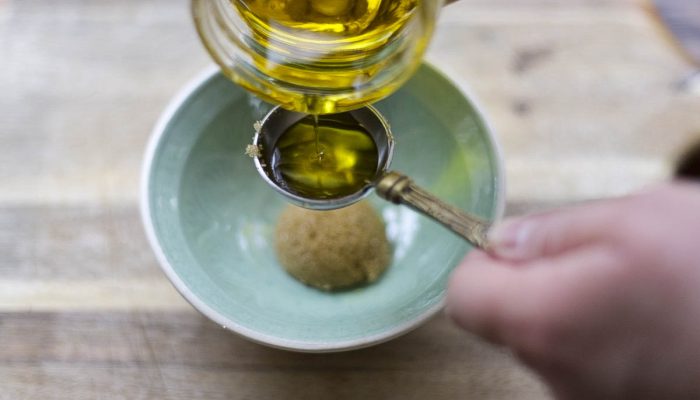 oil being added to brown sugar in a teal bowl