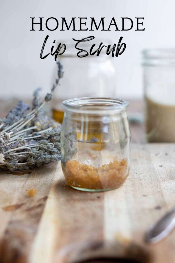 small glass jar with diy lip scrub made with brown sugar on a wood cutting board with dried lavender in the background