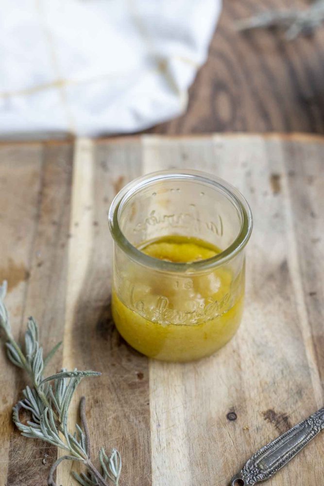 jar of scalp scrub with apple cider in a glass jar on a wood cutting board with lavender around the jar