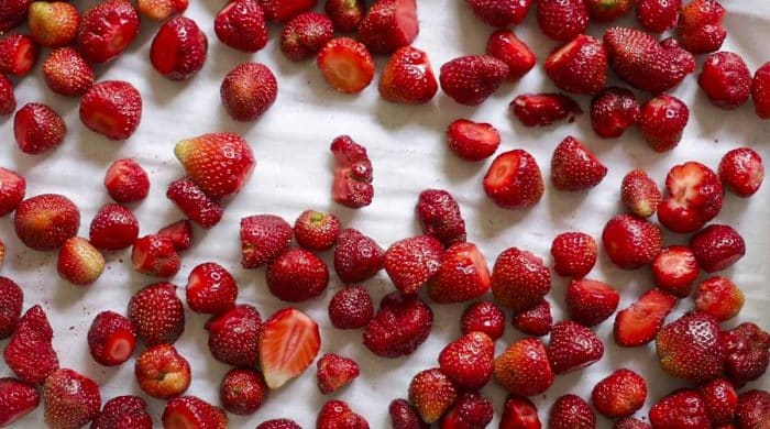strawberries spread out on a parchment lined baking sheet