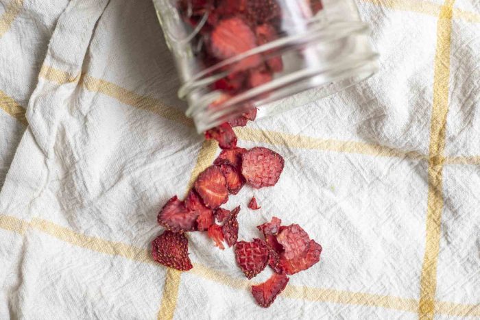 dried strawberries spilled out of a mason jar on a white and yellow towel