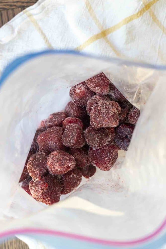 an open bag of frozen strawberries on a white and yellow checked towel