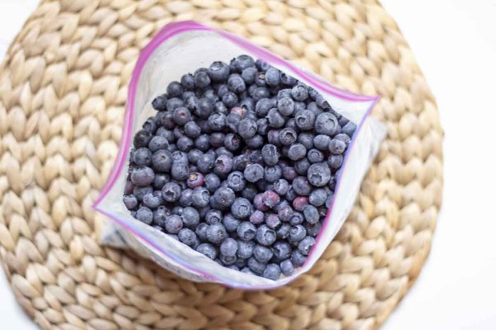 overhead picture of a half a bag of frozen blueberries on a woven mat