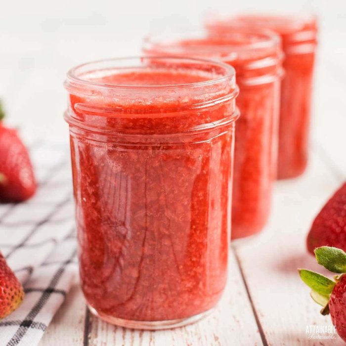 three jars of homemade strawberry jam on a wood countertop