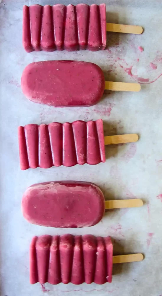 5 strawberry popsicles on a gray countertop