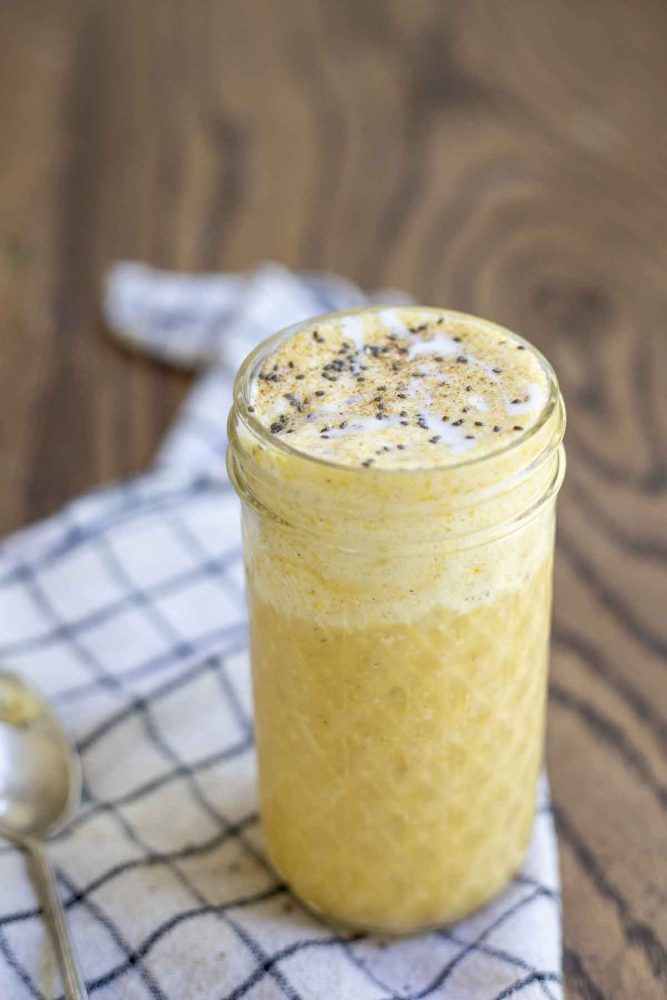 close up of a pumpkin smoothie topped with chia seeds in a glass jar on a white and black checked towel