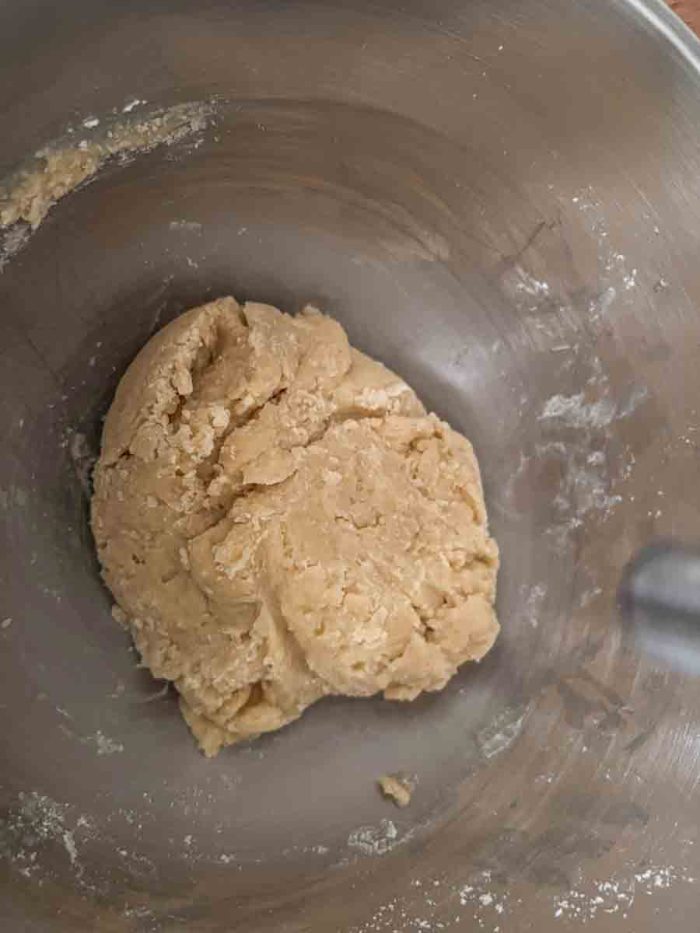 sourdough starter, flour, sugar, and melted butter mixed together to form a dough ball in a stainless bowl