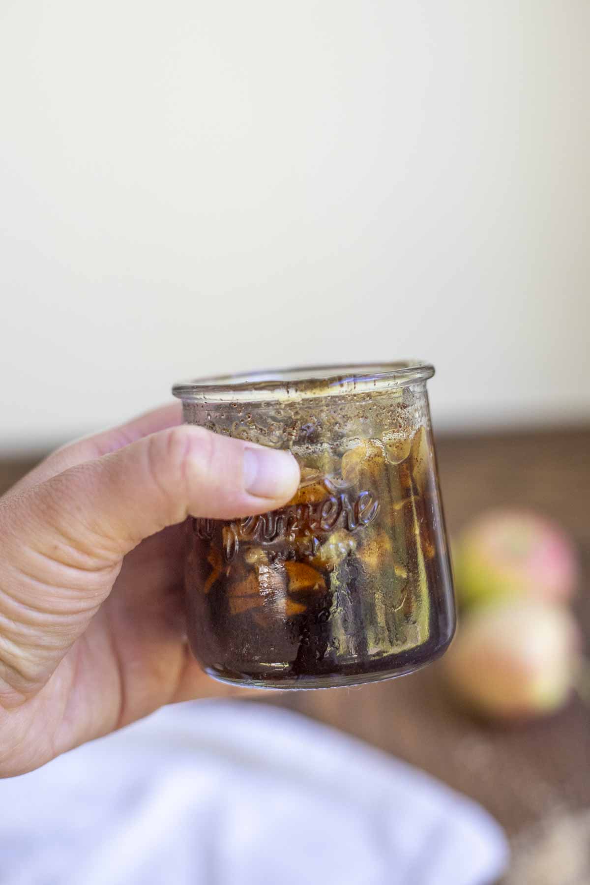 hand holding a small jar of apple syrup.
