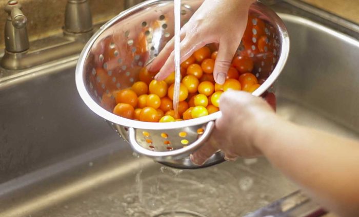 Washing cherry tomatoes in a colander.