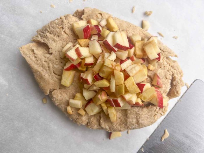 scone dough on parchment paper topped with diced apples