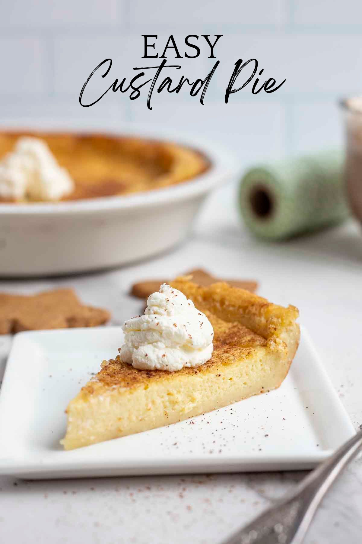 slice of custard pie topped with whipped cream on a white plate  with a pie plate with more pie in the background.