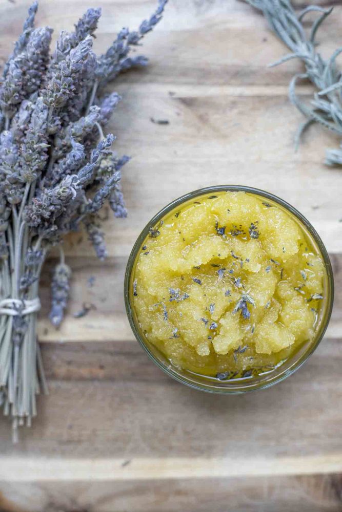 overhead photo of a bundle of dried lavender flowers and a jar of lavender sugar scrub on a wood cutting board