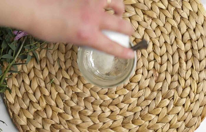 adding sugar to a jar of hot water on a woven mat
