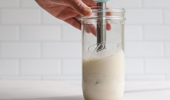 frothed milk that has doubled in size in a jar with a immersion blender