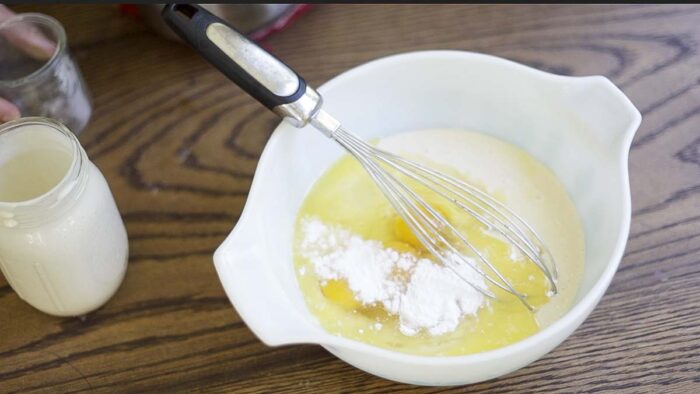 a mixing bowl with sourdough starter, eggs, melted butter and leavening agent.
