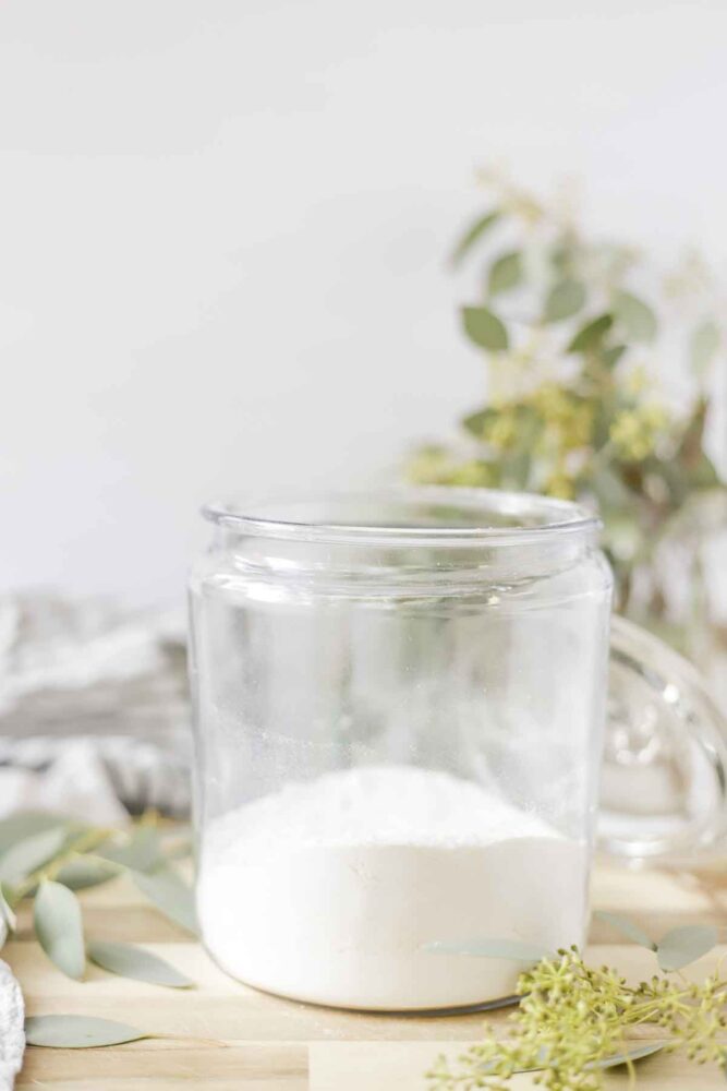 natural and homemade laundry detergent in a glass jar surrounded by eucalyptus 