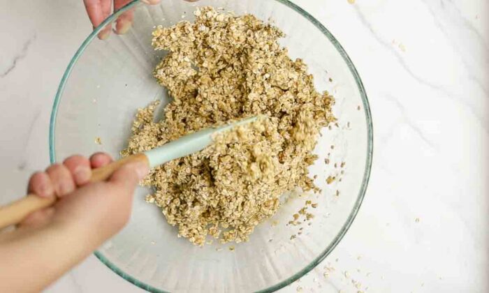 oats in a large bowl being mixed together with starter, honey, and oil.