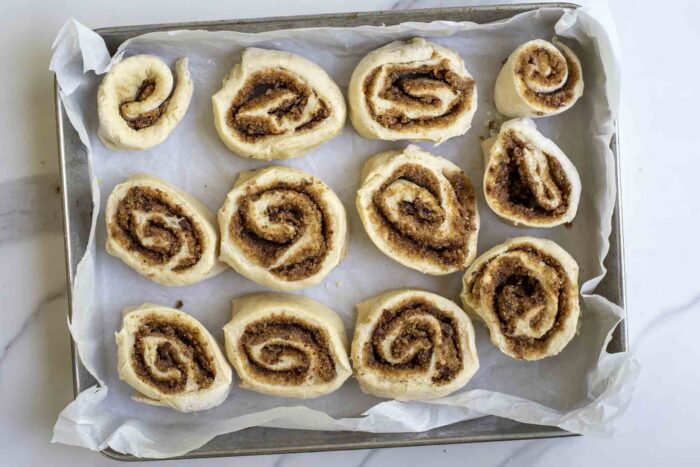 unbaked sourdough cinnamon rolls on a parchment lined baking sheet.