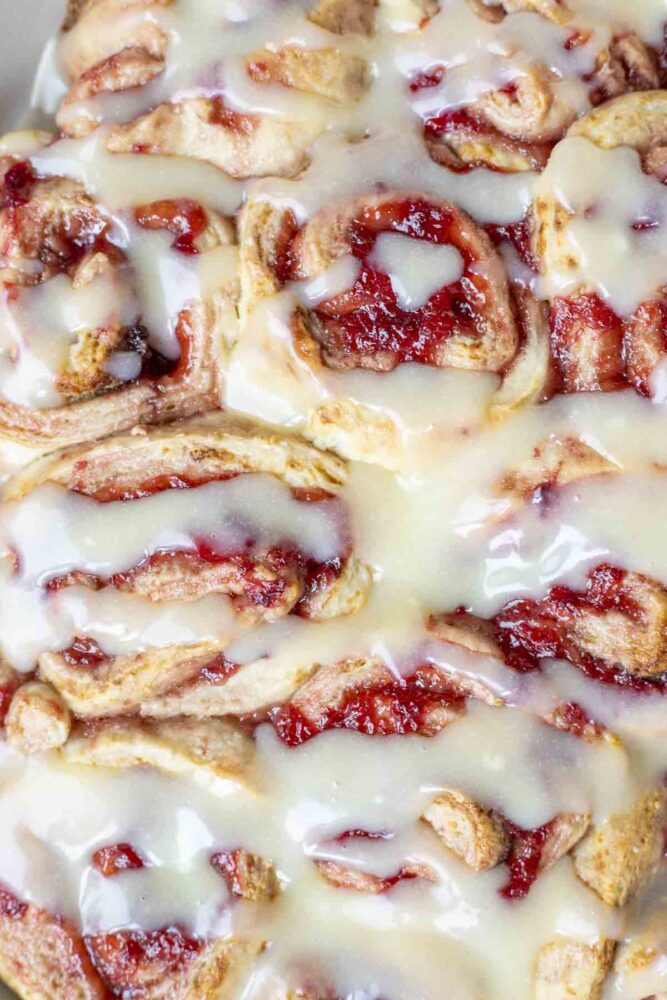 close up of strawberry sourdough rolls drizzled with cream cheese icing