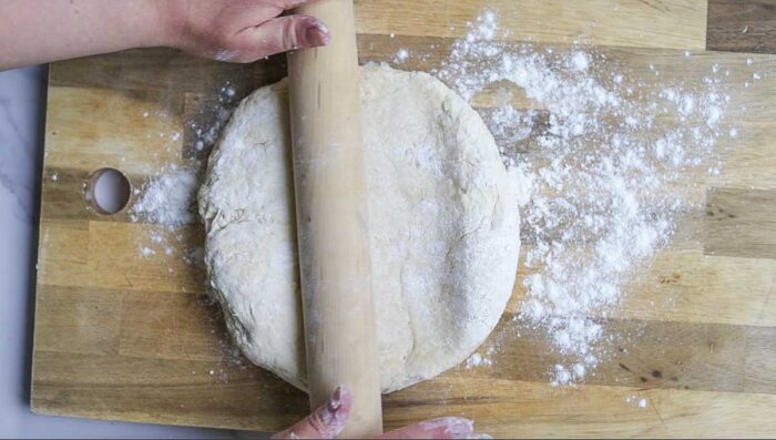 rolling out dough on a floured wood cutting board