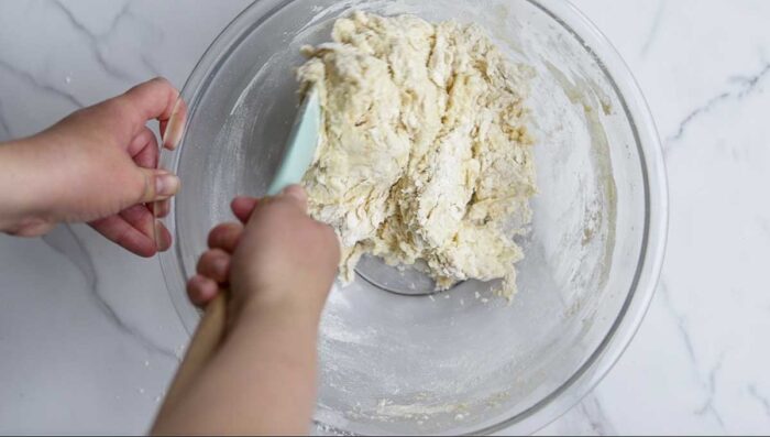 Stirring dough together with a teal silicon spatula