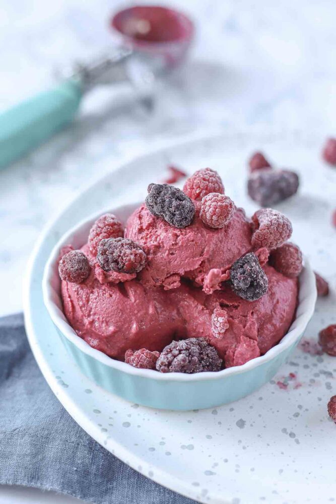 berry frozen yogurt in a teal dish topped with blackberries and raspberries 