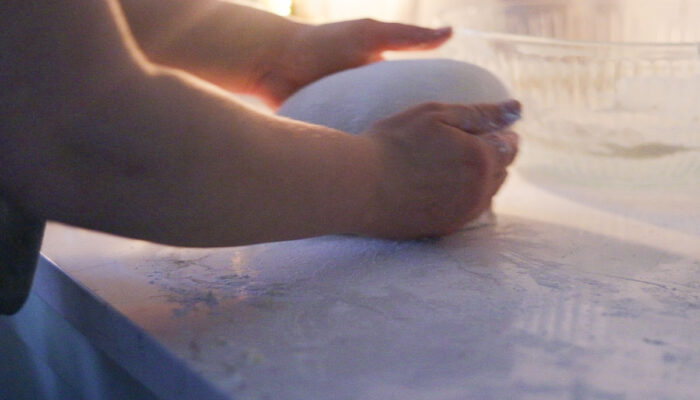 Shaping sourdough bread boule on a quartz countertop.