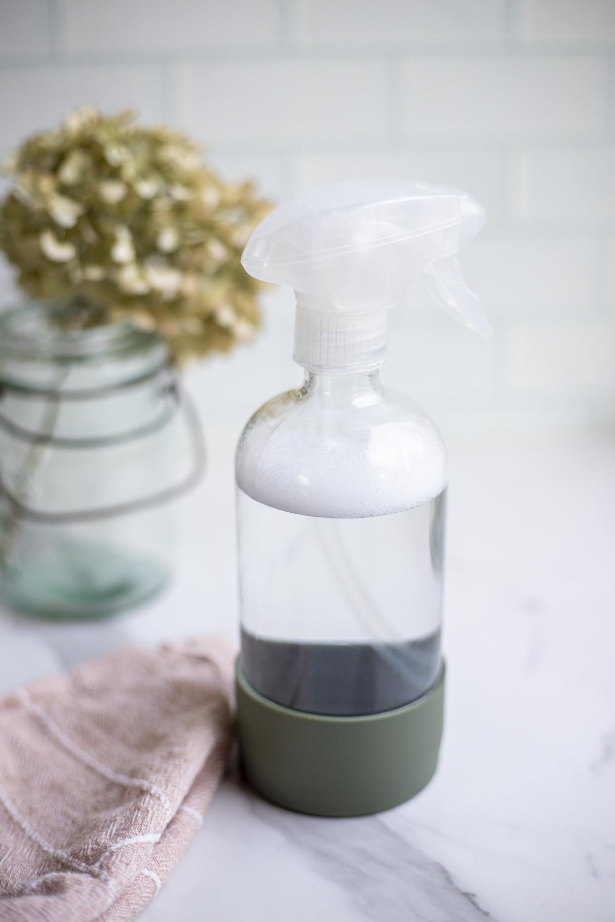 A spray bottle with homemade granite cleaner next to a pink towel.