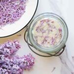 overhead photo of lilac sugar in a jar with lilac flowers surrounding the jar.