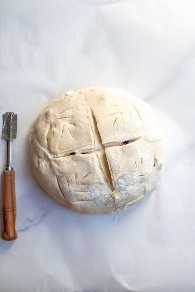 Sourdough bread dough on parchment paper and score with a lame.