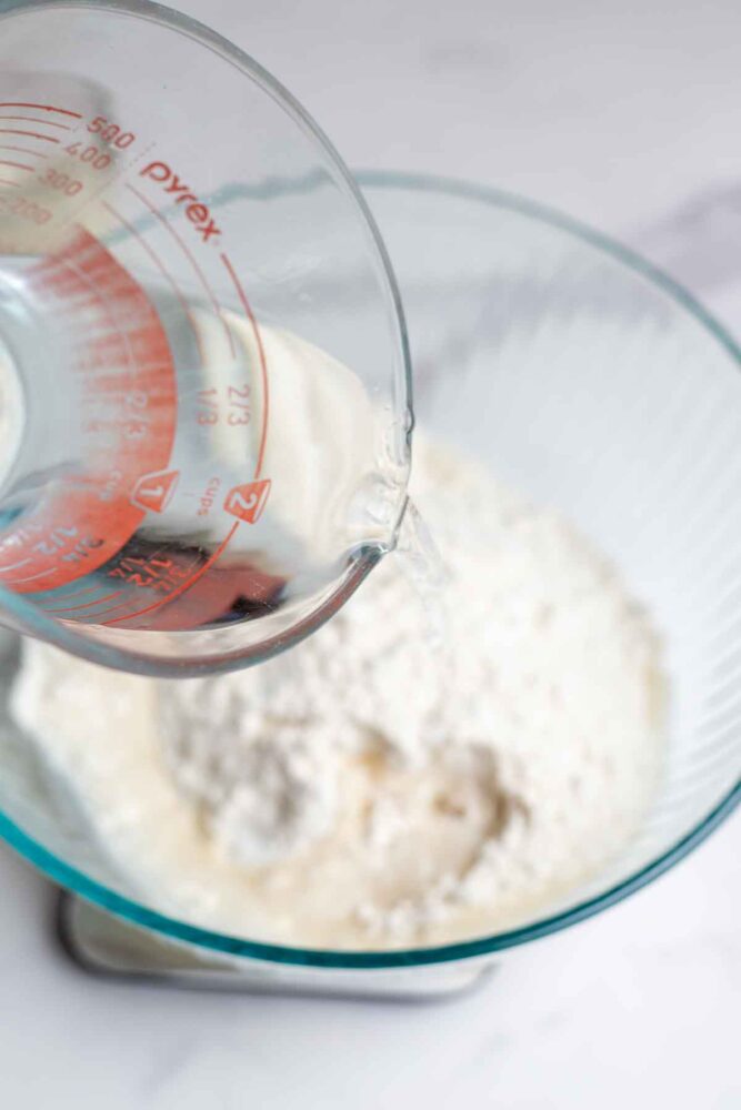 Pouring water into flour on a kitchen scale.