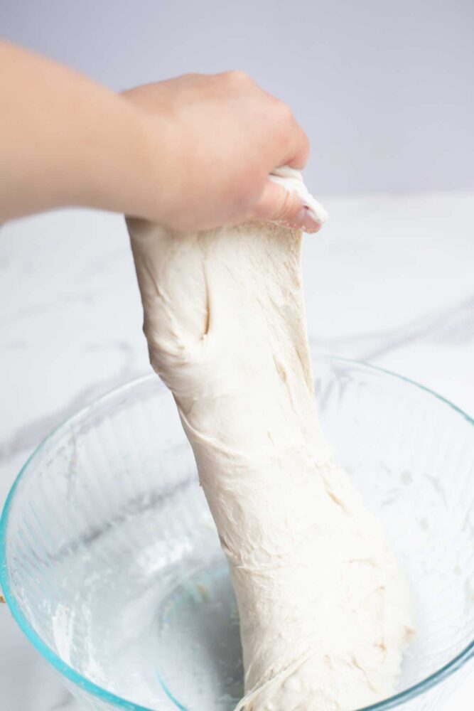 handing pulling up dough for another round of stretch and folds.