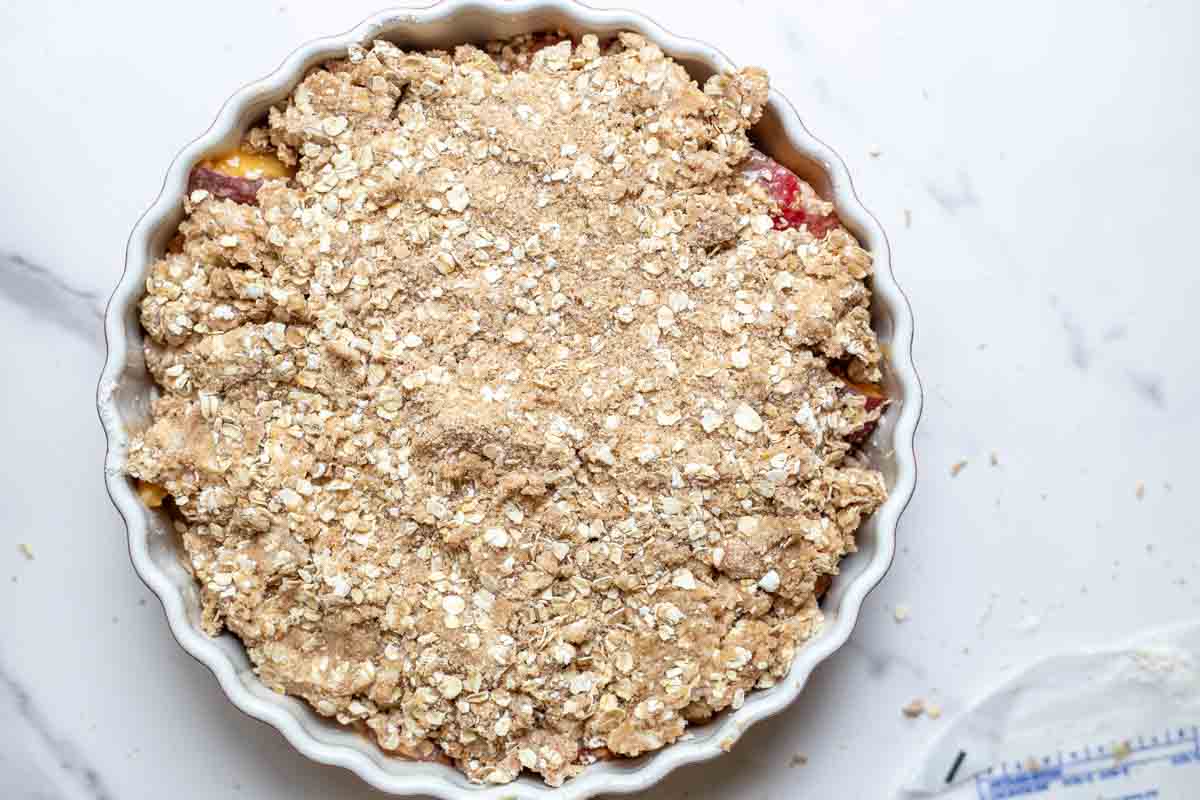 Sourdough crisp topping sprinkled over peaches.