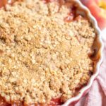 sourdough peach crisp in a baking dish on a pink towel.