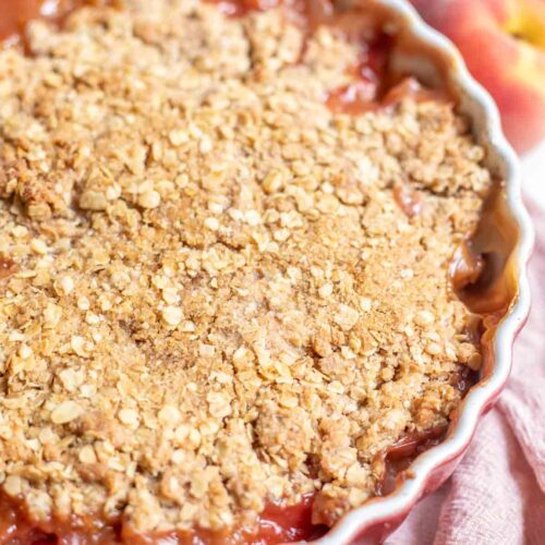 sourdough peach crisp in a baking dish on a pink towel.