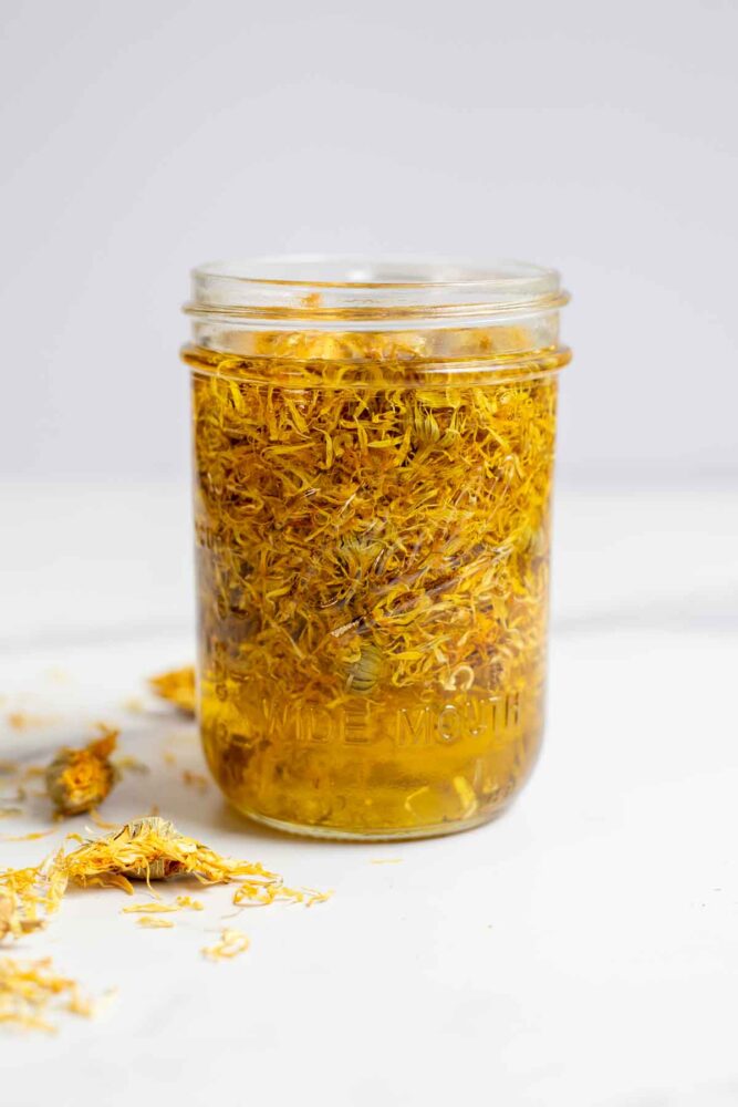 Dried calendula flowers in a mason jar with oil.