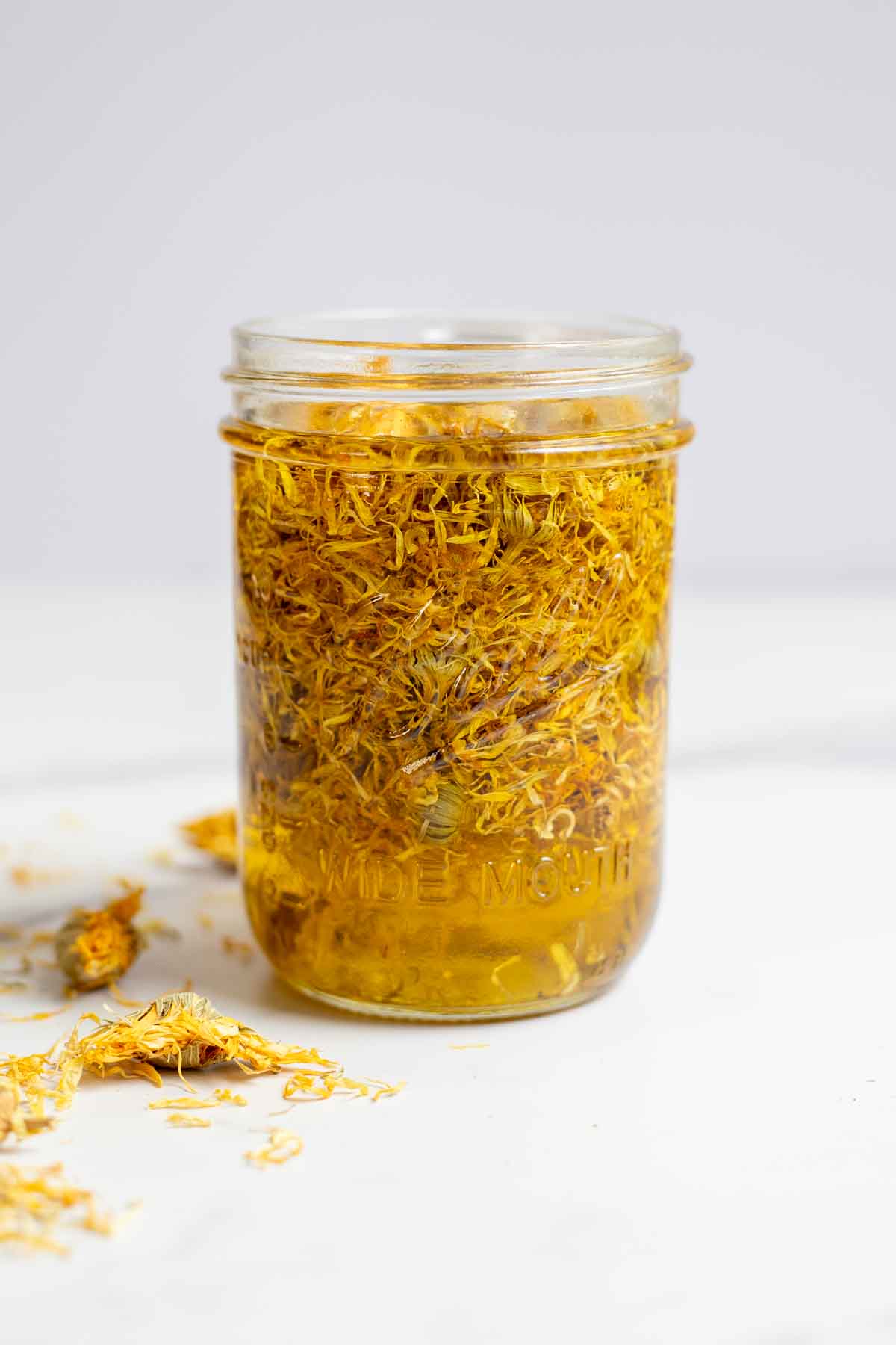 Dried calendula flowers in a mason jar with oil.