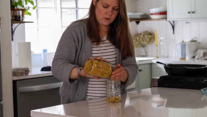 Women adding dried calendulas to a mason jar.