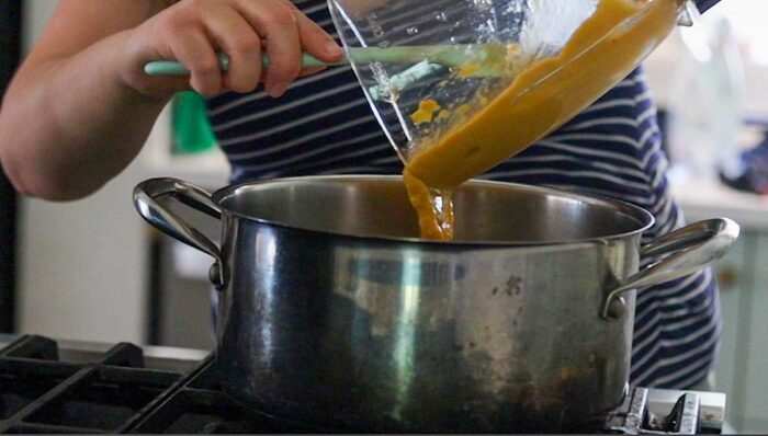 Pouring peach puree into a saucepan. 