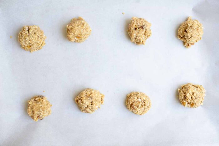 Cookie dough balls on a parchment lined baking sheet.