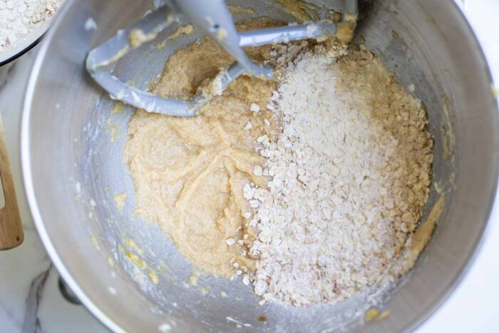Slowly adding dry ingredients to the wet ingredients in a stand mixer bowl.