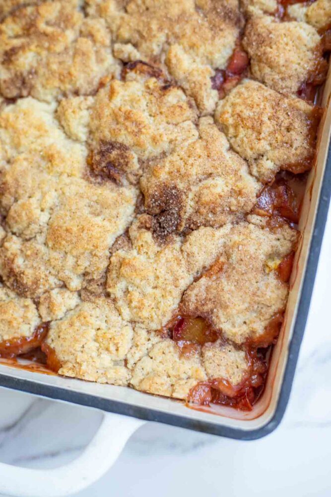 Overhead photo of the corner of a baking dish with sourdough discard peach cobbler.