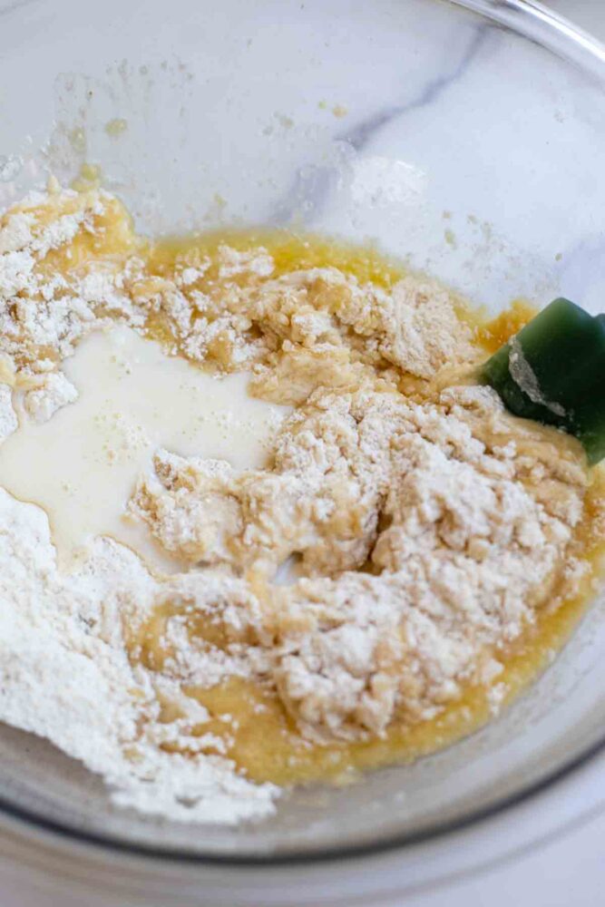 Adding wet ingredients to dry ingredients in a glass bowl.