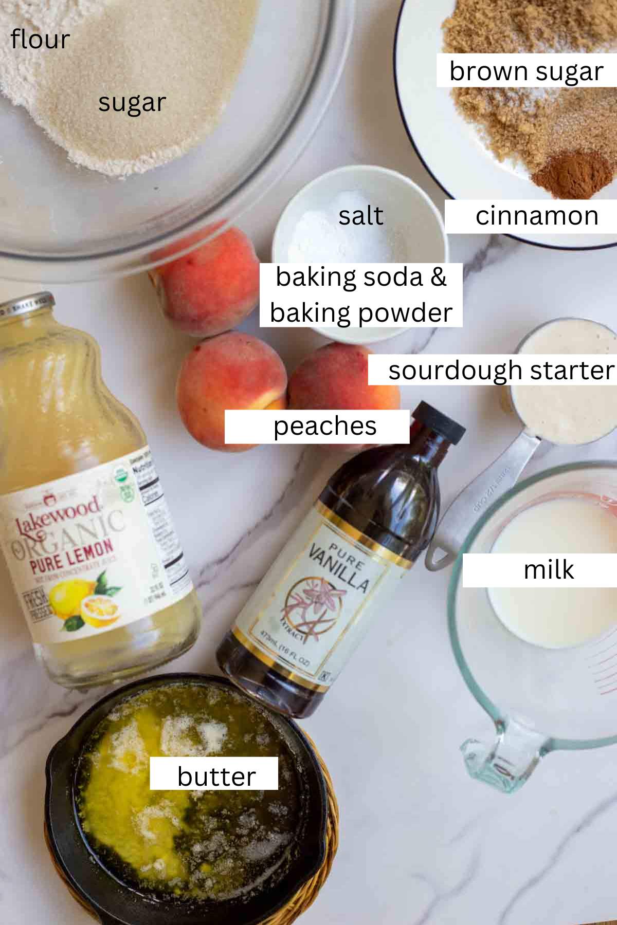 Flour, sugar, butter, peaches, sourdough starter and more on a countertop.