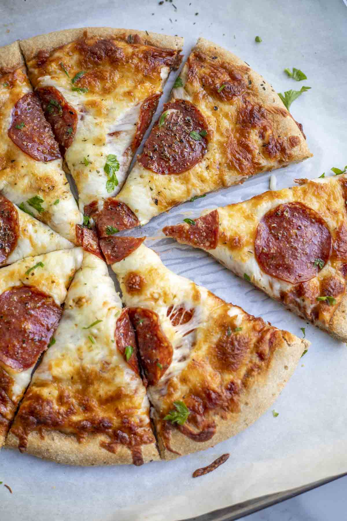Whole wheat sourdough pizza topped with cheese, pepperoni, and fresh herbs.