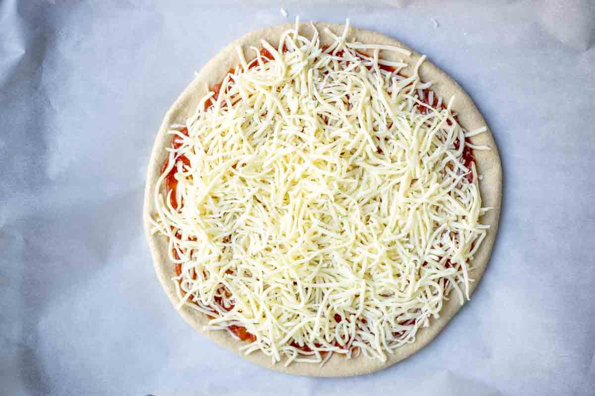 Sauce and cheese added to whole wheat pizza dough.