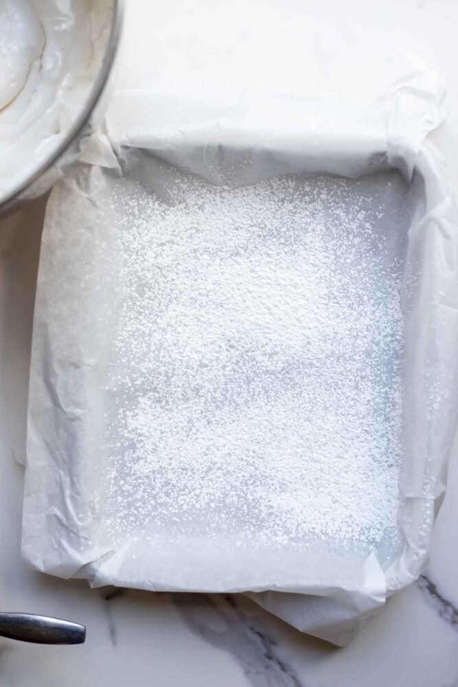 A pan lined with parchment paper and sprinkled with powdered sugar and cornstarch.