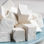 Homemade marshmallows stacked on a blue plate.